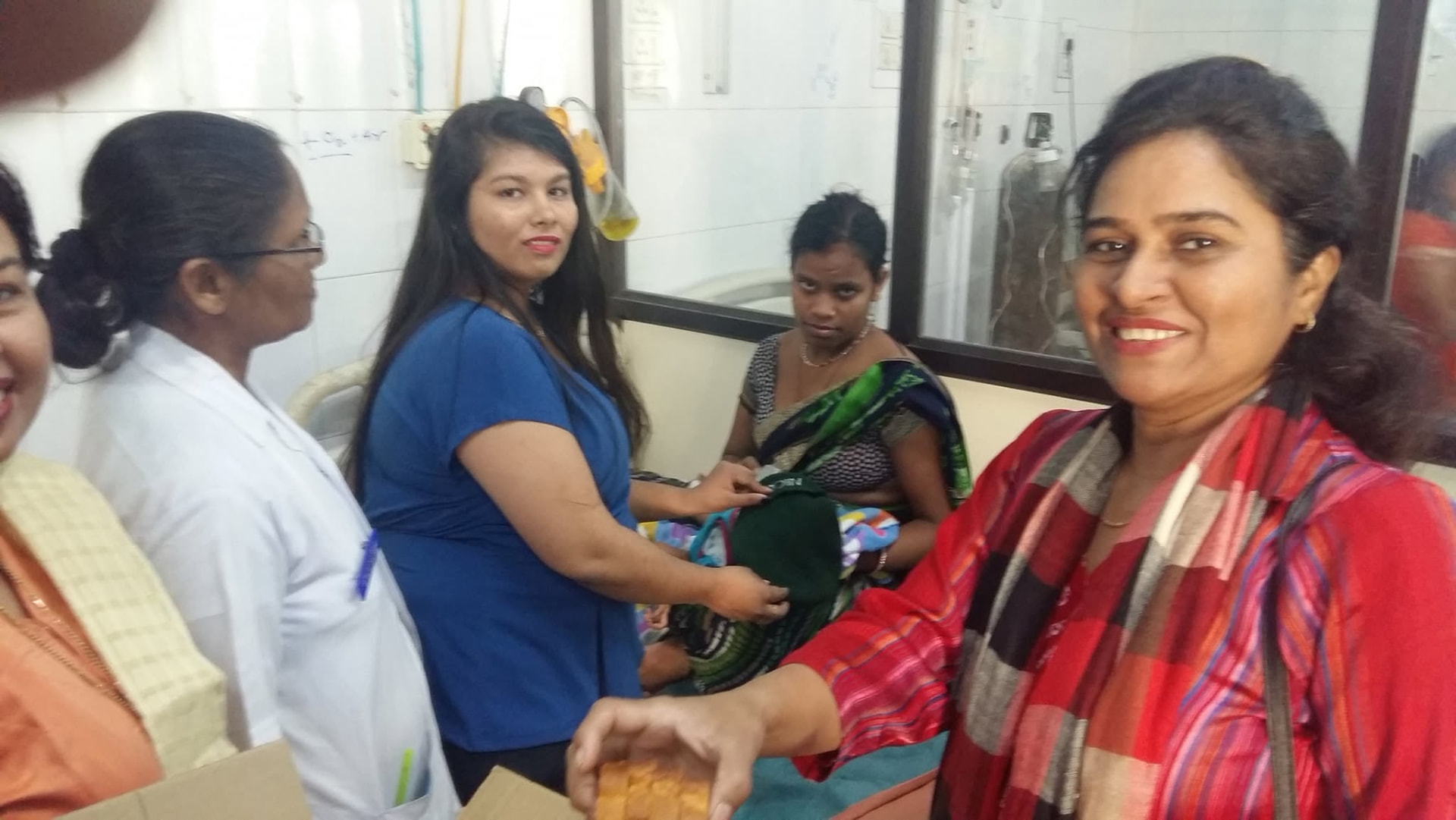 Volunteers handing warm caps to a mother and hospital staff