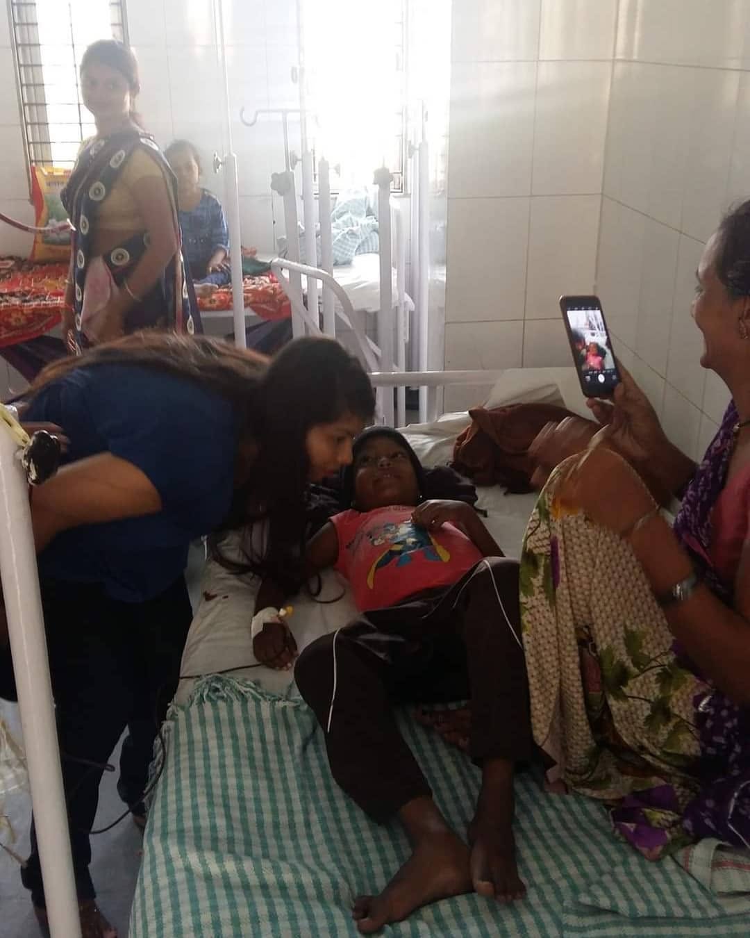 A volunteer comforting a child in a hospital bed during the cap distribution