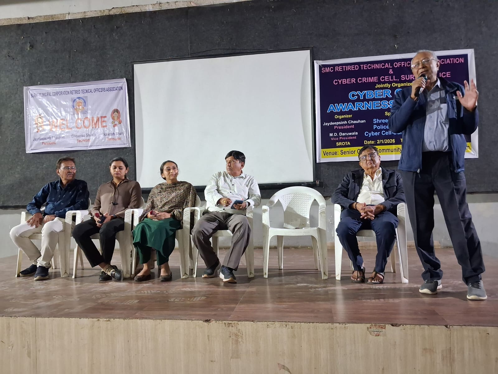 Guests seated on stage as a speaker addresses an awareness seminar audience