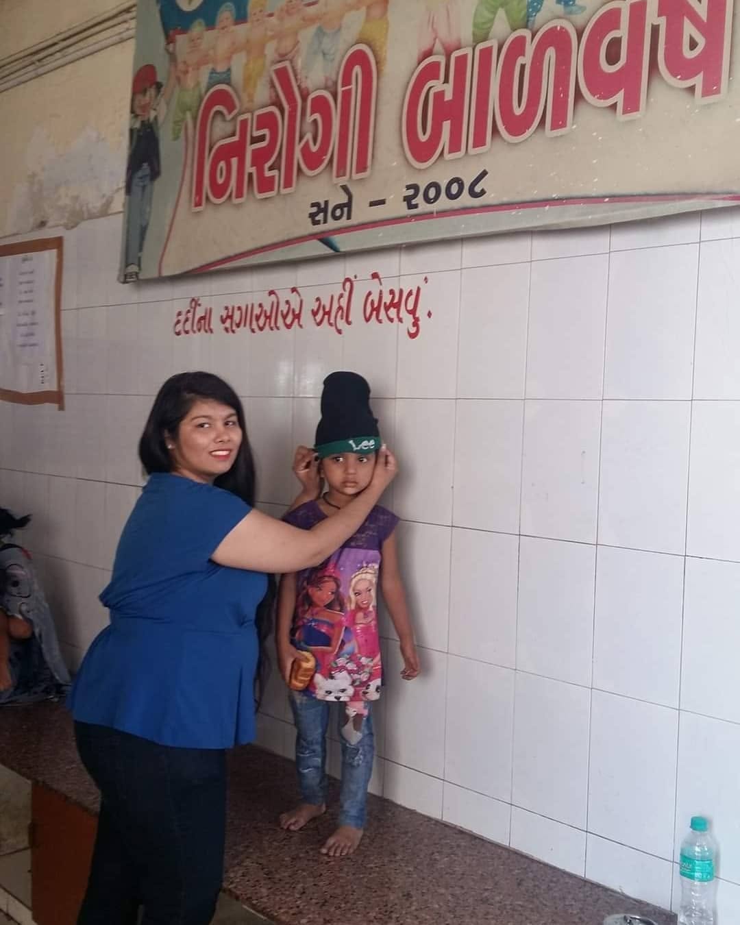 A volunteer fitting a warm winter cap on a young girl at the hospital