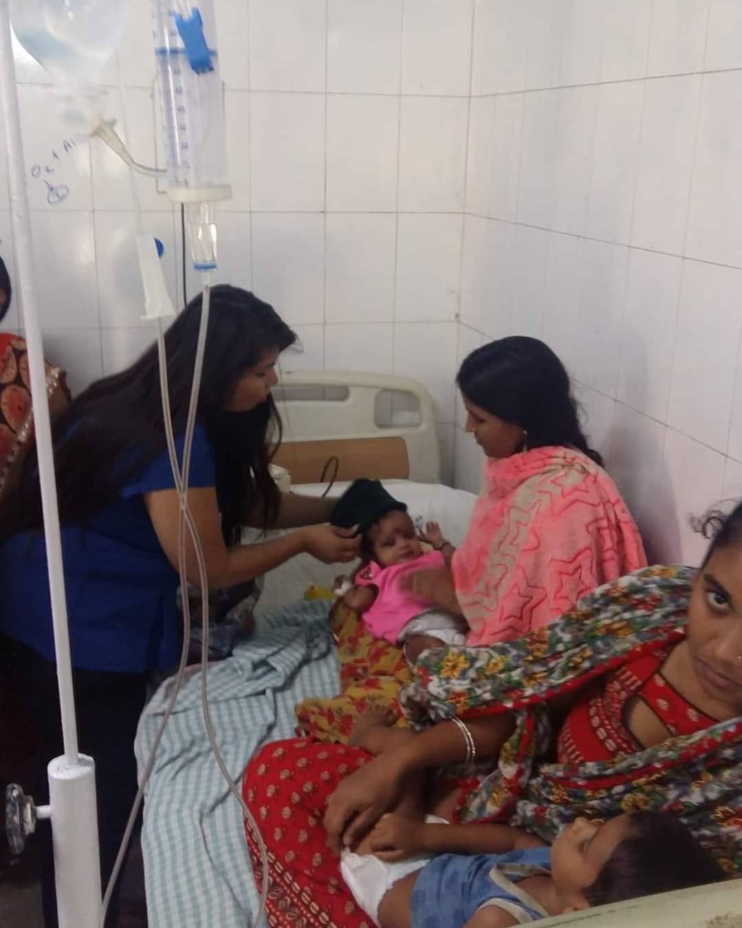 A volunteer placing a warm cap on an infant in a hospital ward