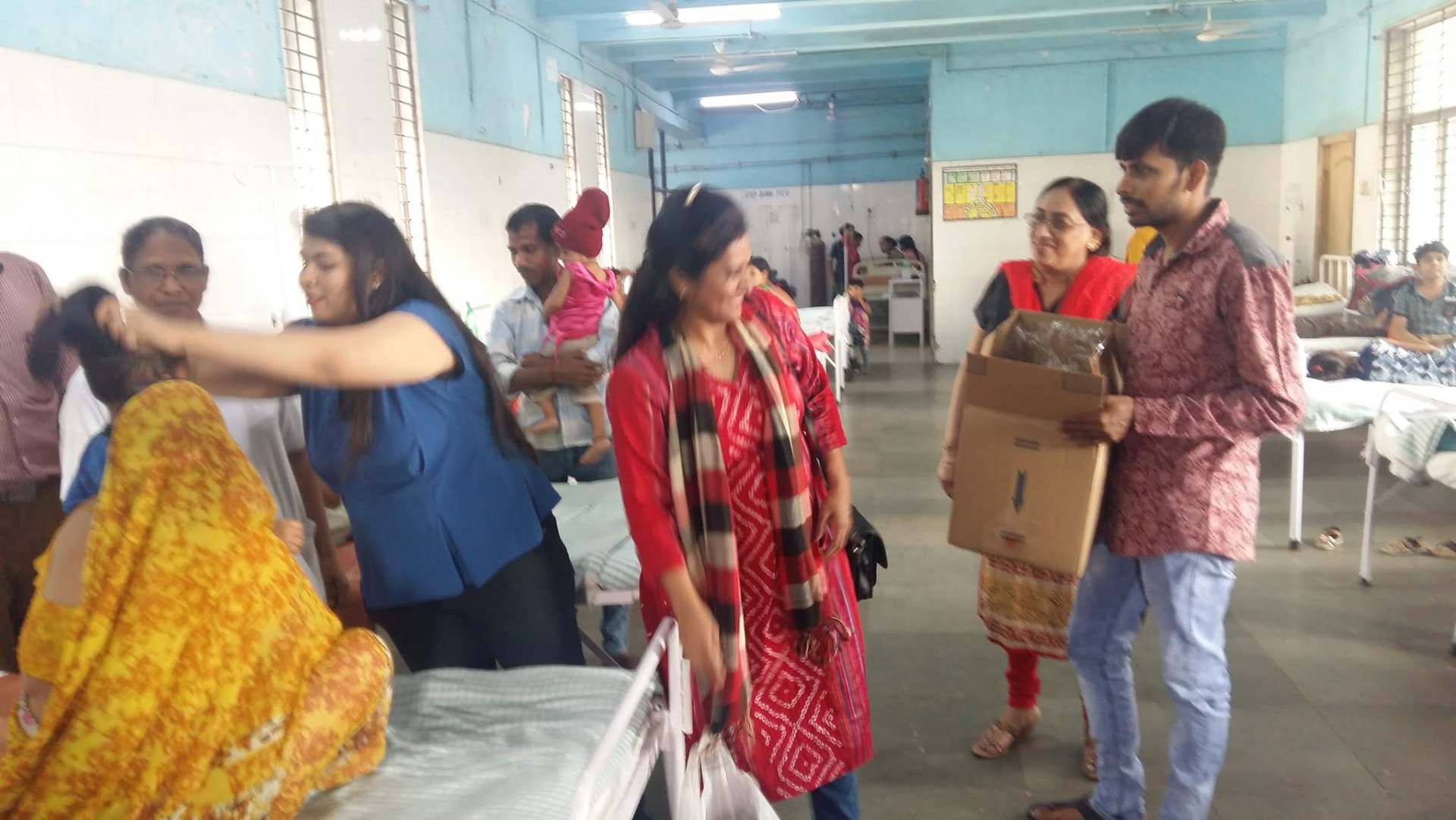 Volunteers carrying cartons of warm caps through a hospital ward