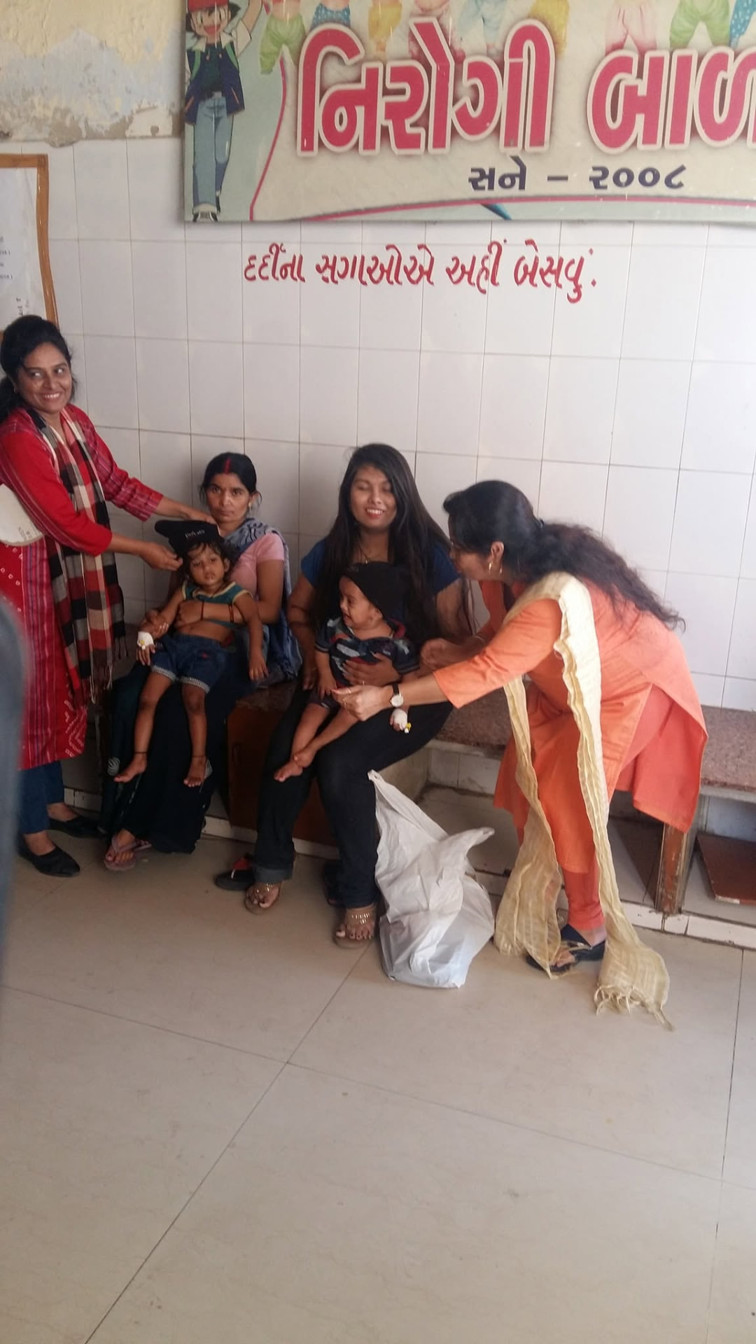 Volunteers putting warm caps on children waiting with their mothers at the hospital